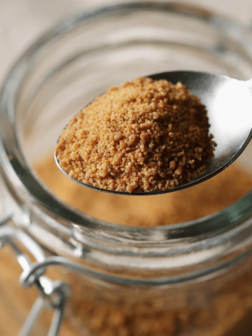 Spoon of brown sugar in a glass bowl, closeup shop